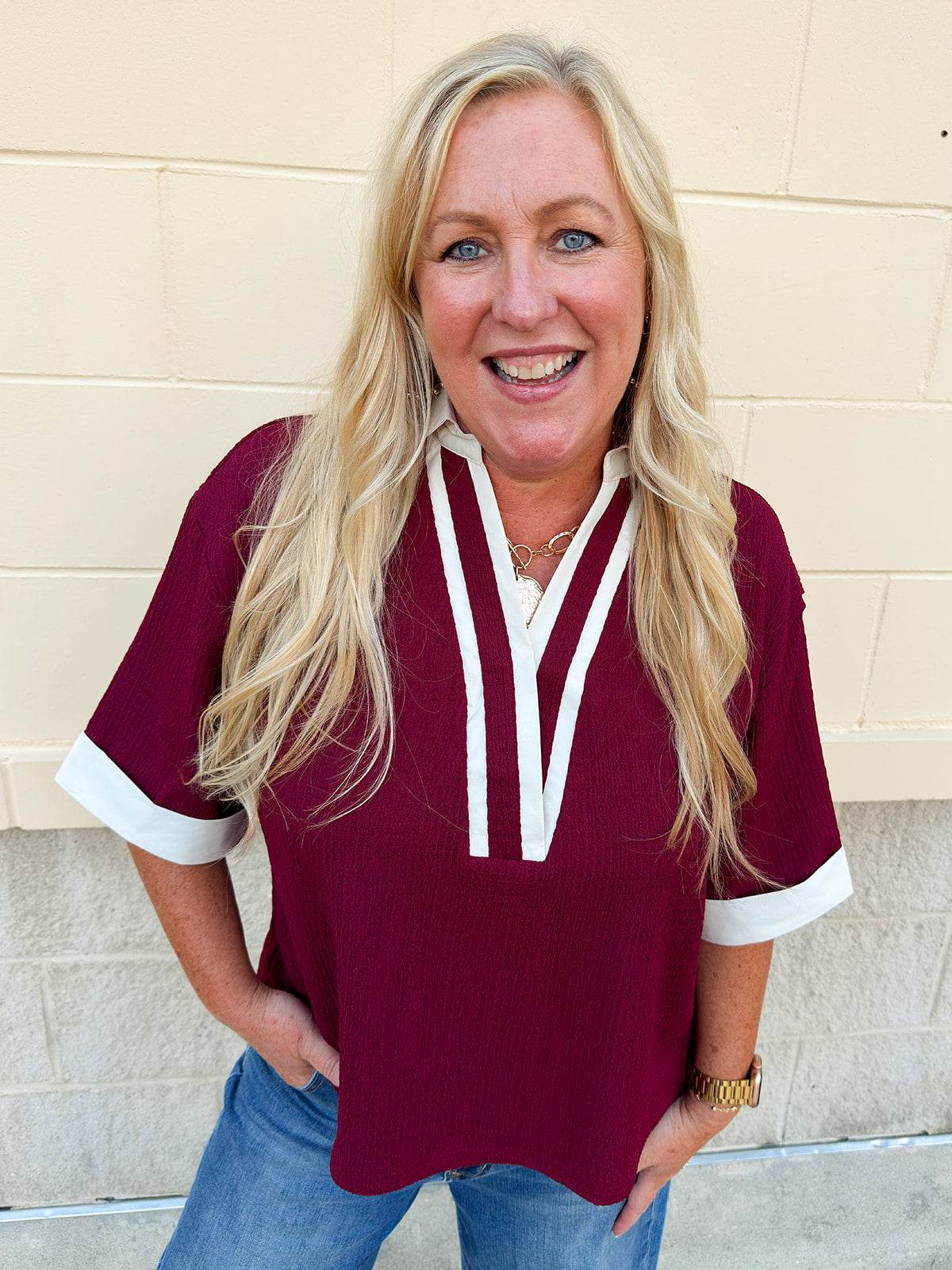 Burgundy boxy fit V-neck top with white contrast trim at neckline, collar, and sleeve cuffs.
