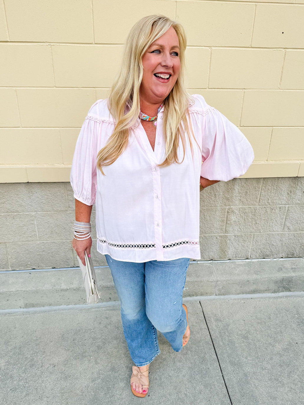 Solid pink button-down blouse with circular eyelet trim, ¾ sleeves, and pleated details, styled for a refined, feminine look.
