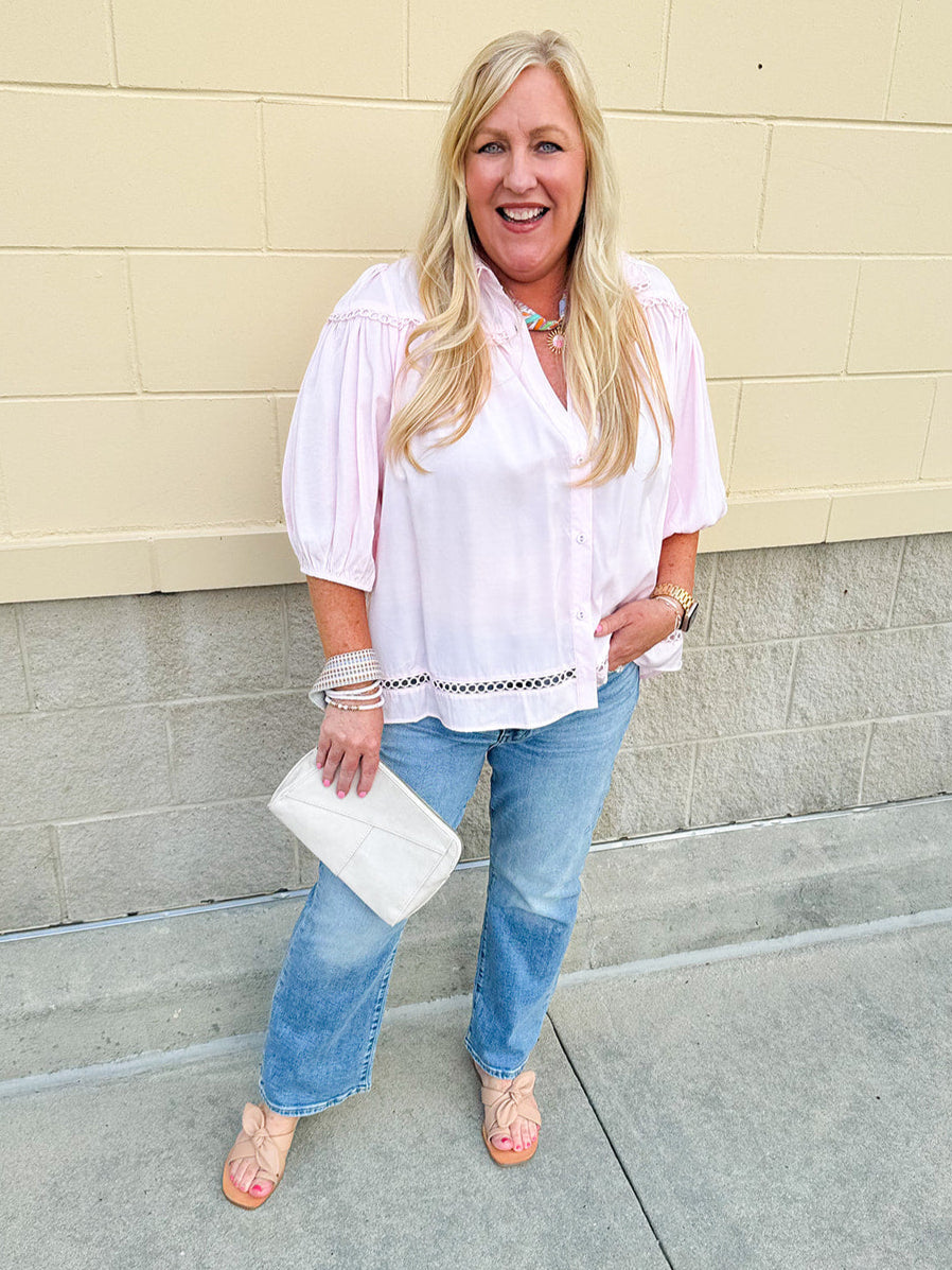 Solid pink button-down blouse with circular eyelet trim, ¾ sleeves, and pleated details, styled for a refined, feminine look.