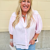 Solid pink button-down blouse with circular eyelet trim, ¾ sleeves, and pleated details, styled for a refined, feminine look.