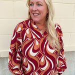 Garnet, gold, and cream geometric print top with long sleeves, v-neckline, and ruffled neckline.
