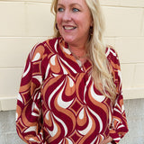 Garnet, gold, and cream geometric print top with long sleeves, v-neckline, and ruffled neckline.