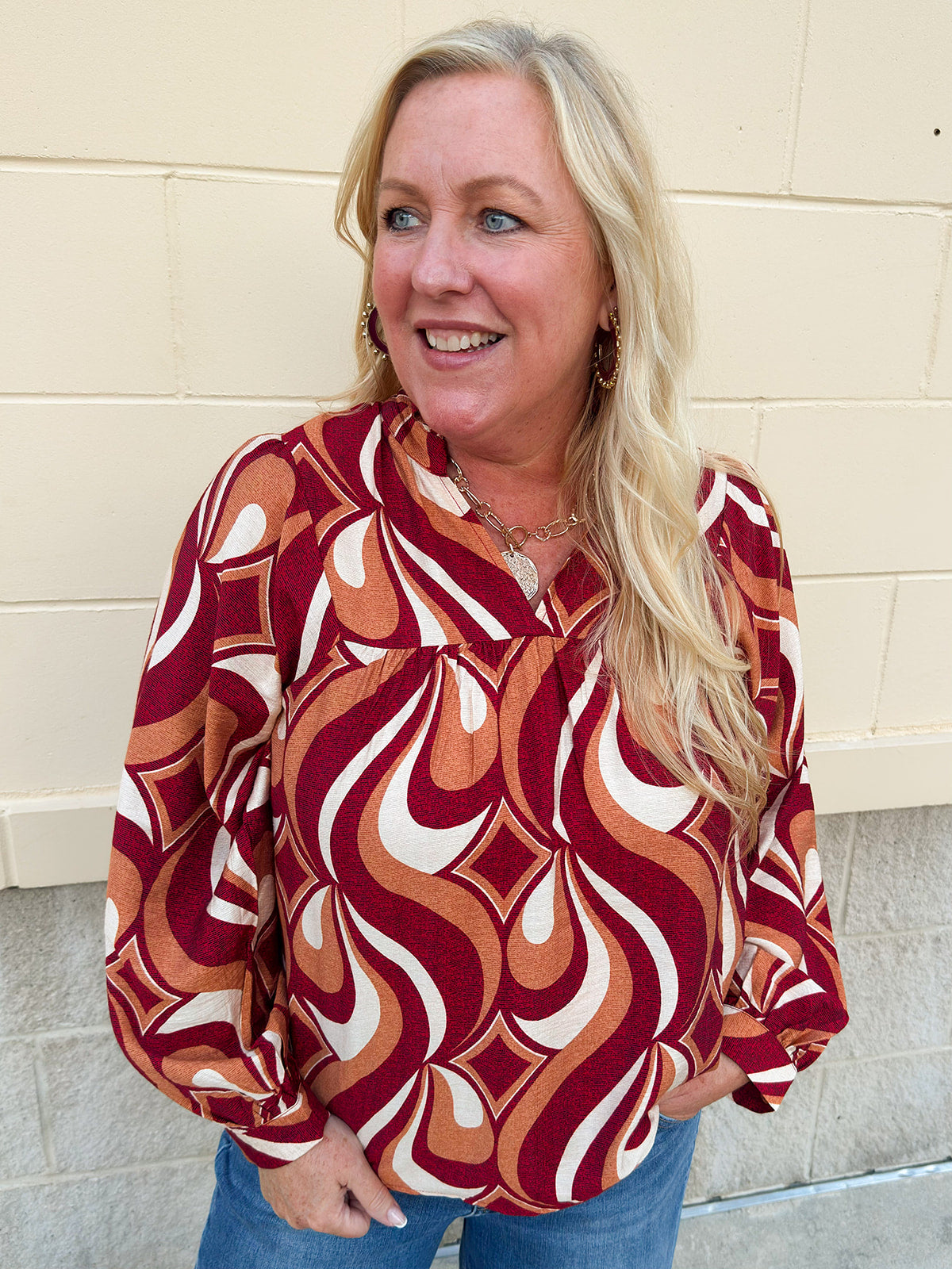 Garnet, gold, and cream geometric print top with long sleeves, v-neckline, and ruffled neckline.