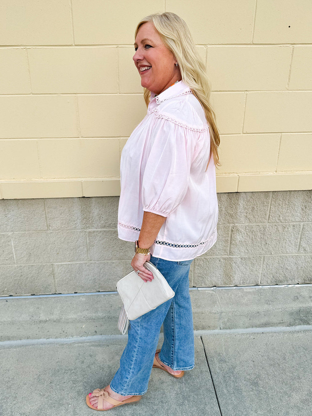Solid pink button-down blouse with circular eyelet trim, ¾ sleeves, and pleated details, styled for a refined, feminine look.