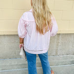 Solid pink button-down blouse with circular eyelet trim, ¾ sleeves, and pleated details, styled for a refined, feminine look.