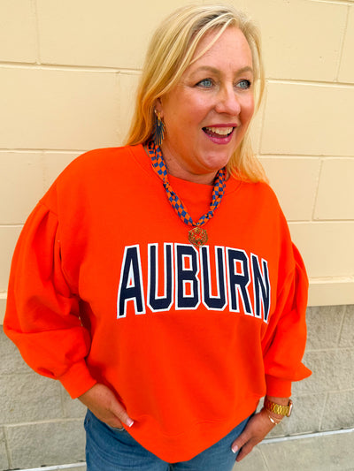 Women's orange fleece crewneck sweatshirt featuring oversized Auburn collegiate graphics with vintage chenille detailing and a relaxed fit.