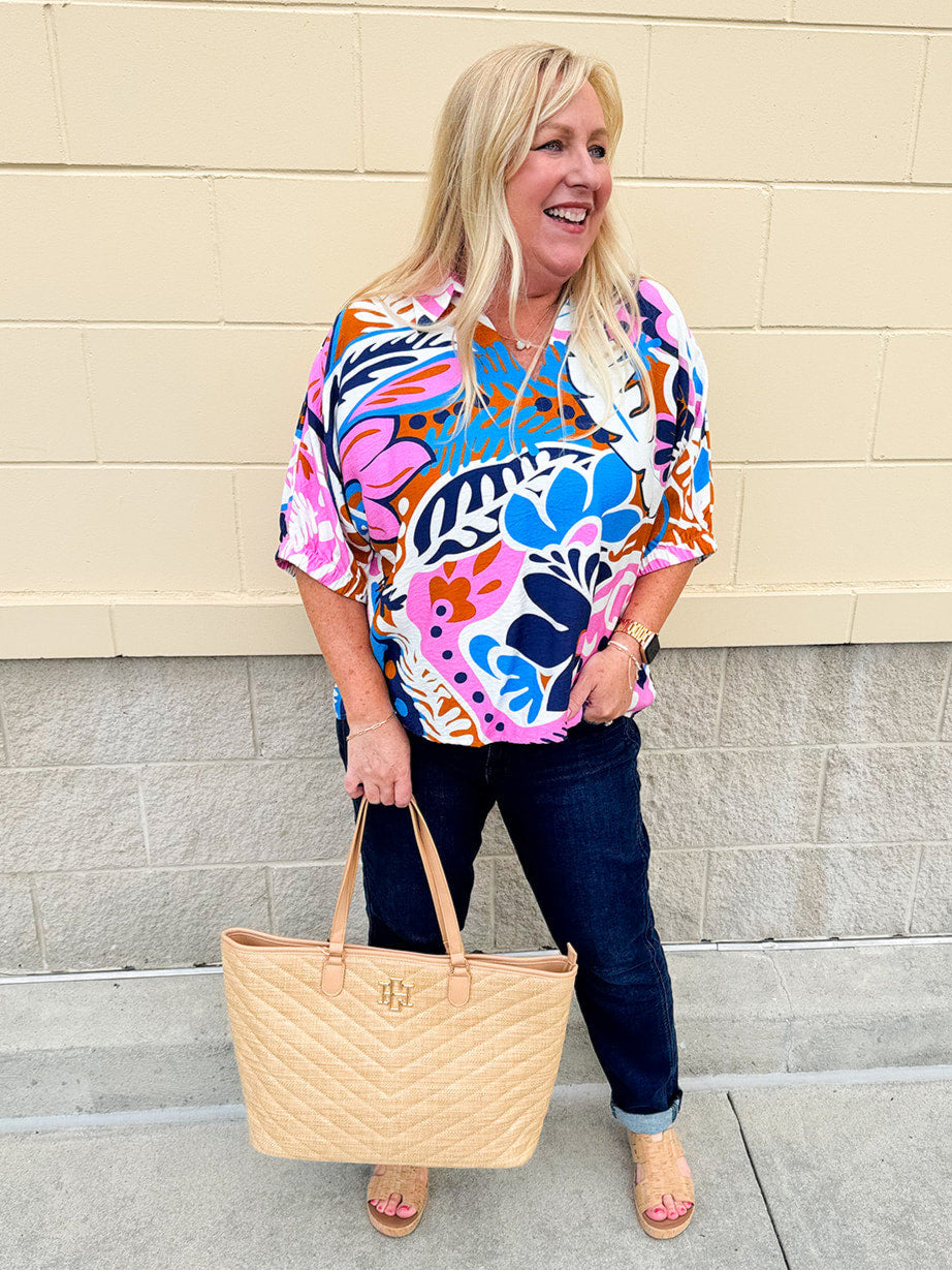 Abstract floral print top with a collared neckline, loose fit, dolman sleeves, and elastic arm cuffs—bright, relaxed, and feminine.