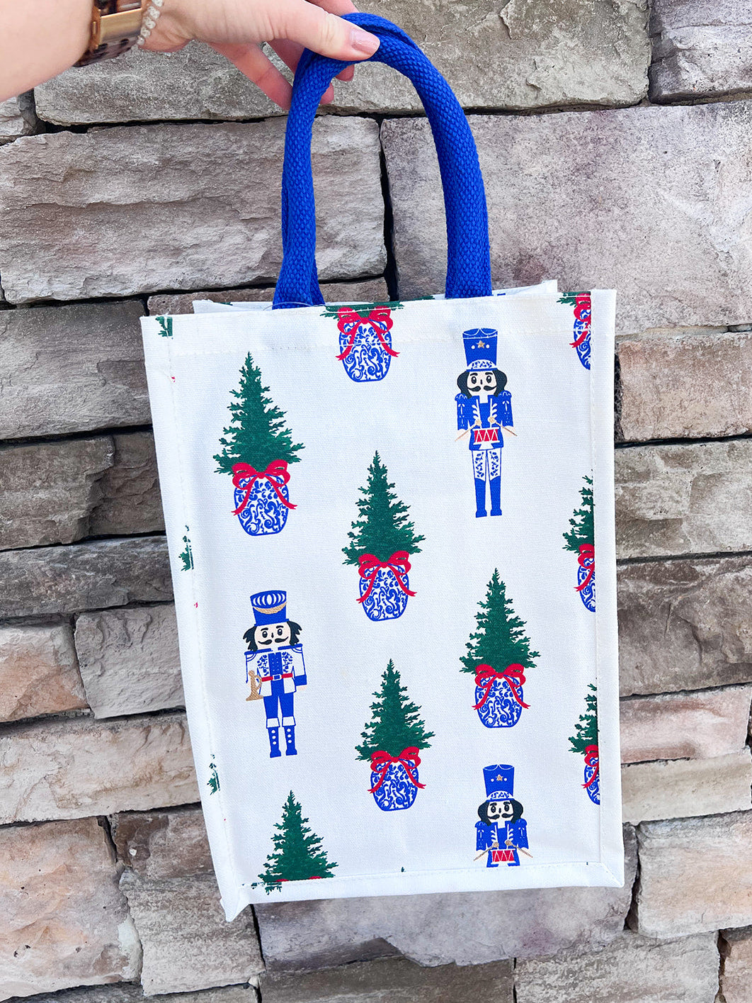 White wine caddy with nutcracker and Christmas tree print, blue handles.