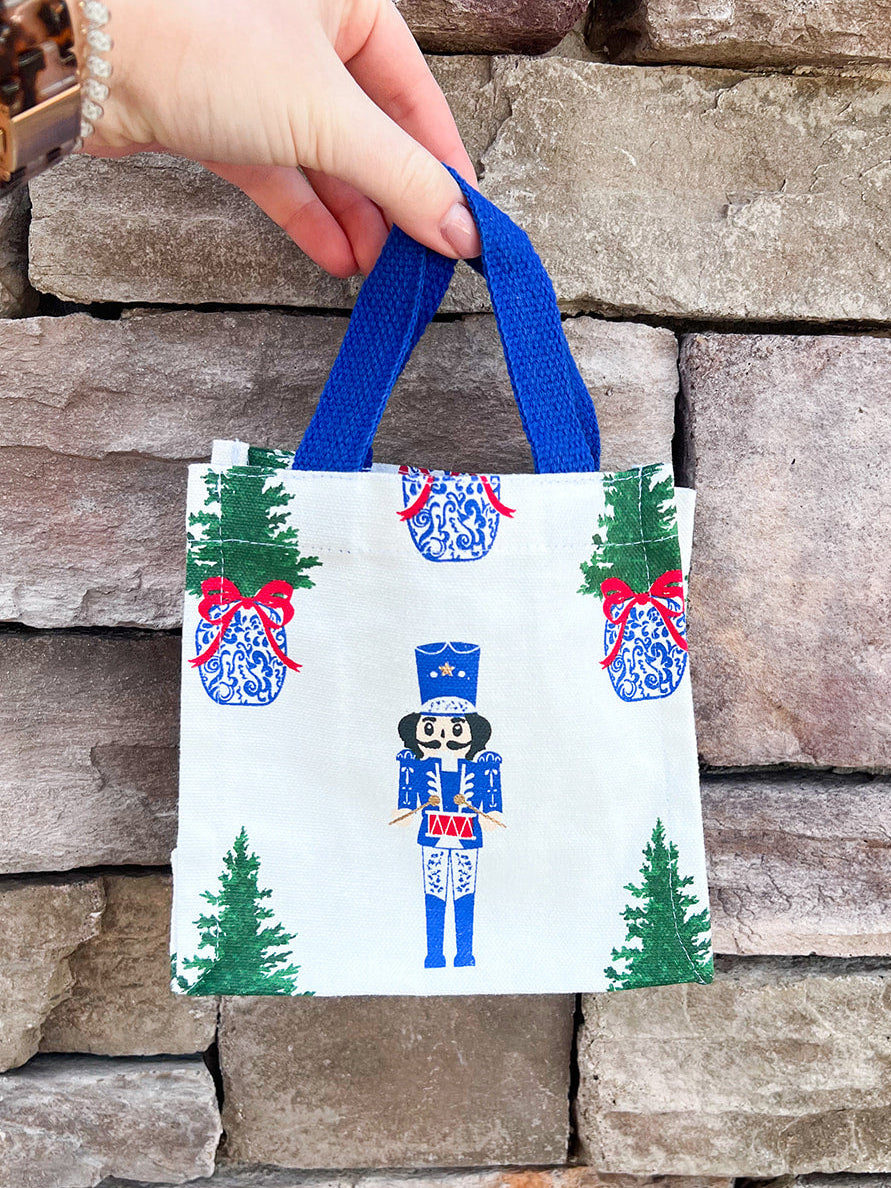 White wine caddy with nutcracker and Christmas tree print, blue handles.