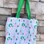 Tote bag with festive design featuring pink doors, green wreaths, and ribbons on a white background.