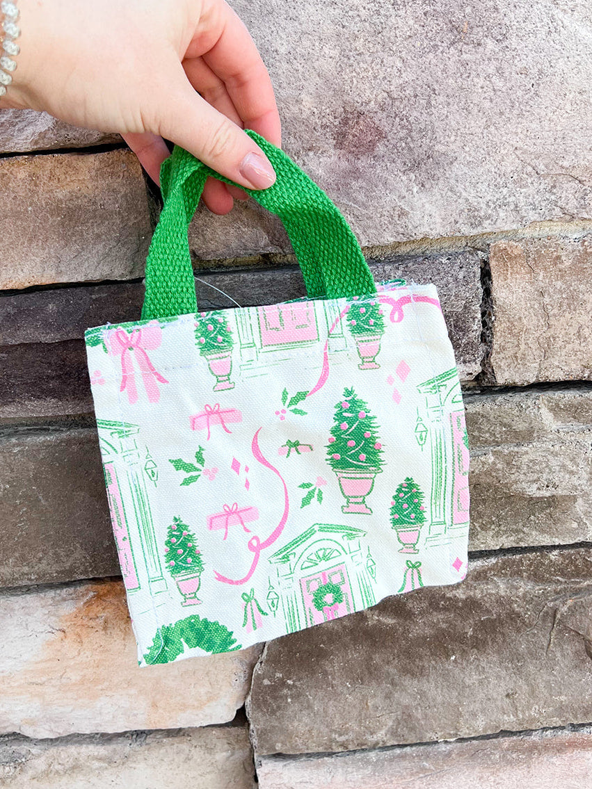 Small tote bag with Christmas-themed design featuring trees, wreaths, and presents on a white background.