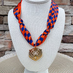 Orange and navy checkerboard scarf necklace with a gold-tone tiger head pendant.