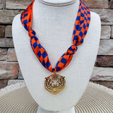 Orange and navy checkerboard scarf necklace with a gold-tone tiger head pendant.