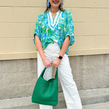 White caftan top with green and blue abstract floral print, split neckline, and dolman sleeves with elastic cuffs—lightweight and flowy