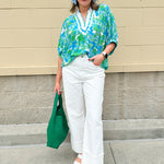 White caftan top with green and blue abstract floral print, split neckline, and dolman sleeves with elastic cuffs—lightweight and flowy