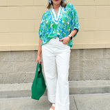 White caftan top with green and blue abstract floral print, split neckline, and dolman sleeves with elastic cuffs—lightweight and flowy
