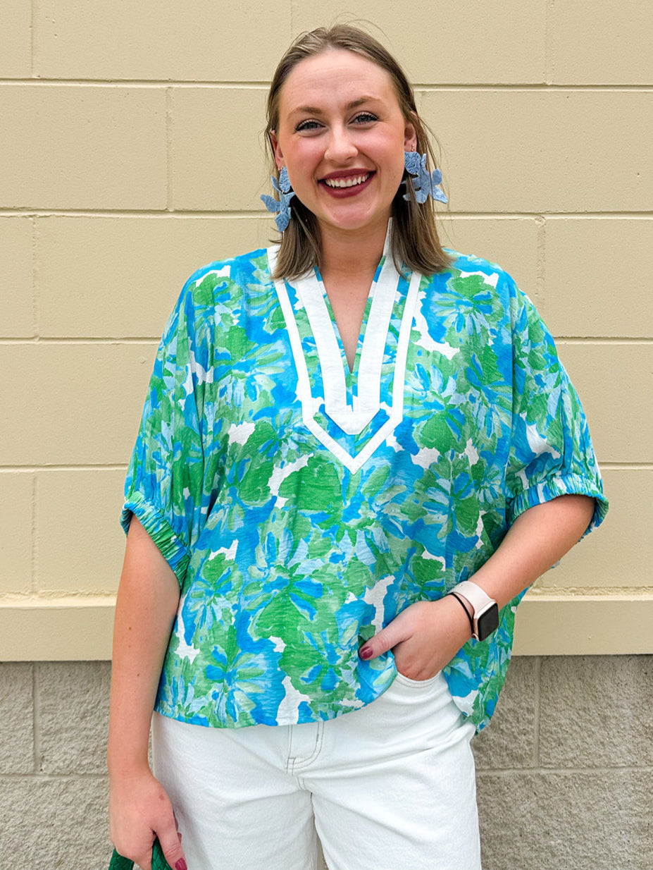 White caftan top with green and blue abstract floral print, split neckline, and dolman sleeves with elastic cuffs—lightweight and flowy