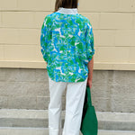 White caftan top with green and blue abstract floral print, split neckline, and dolman sleeves with elastic cuffs—lightweight and flowy