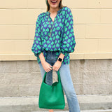 Flowy navy and green patterned blouse with tie-neck, ruffle collar, dolman sleeves, and elastic cuffs—lightweight and oversized