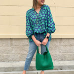 Flowy navy and green patterned blouse with tie-neck, ruffle collar, dolman sleeves, and elastic cuffs—lightweight and oversized