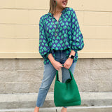 Flowy navy and green patterned blouse with tie-neck, ruffle collar, dolman sleeves, and elastic cuffs—lightweight and oversized