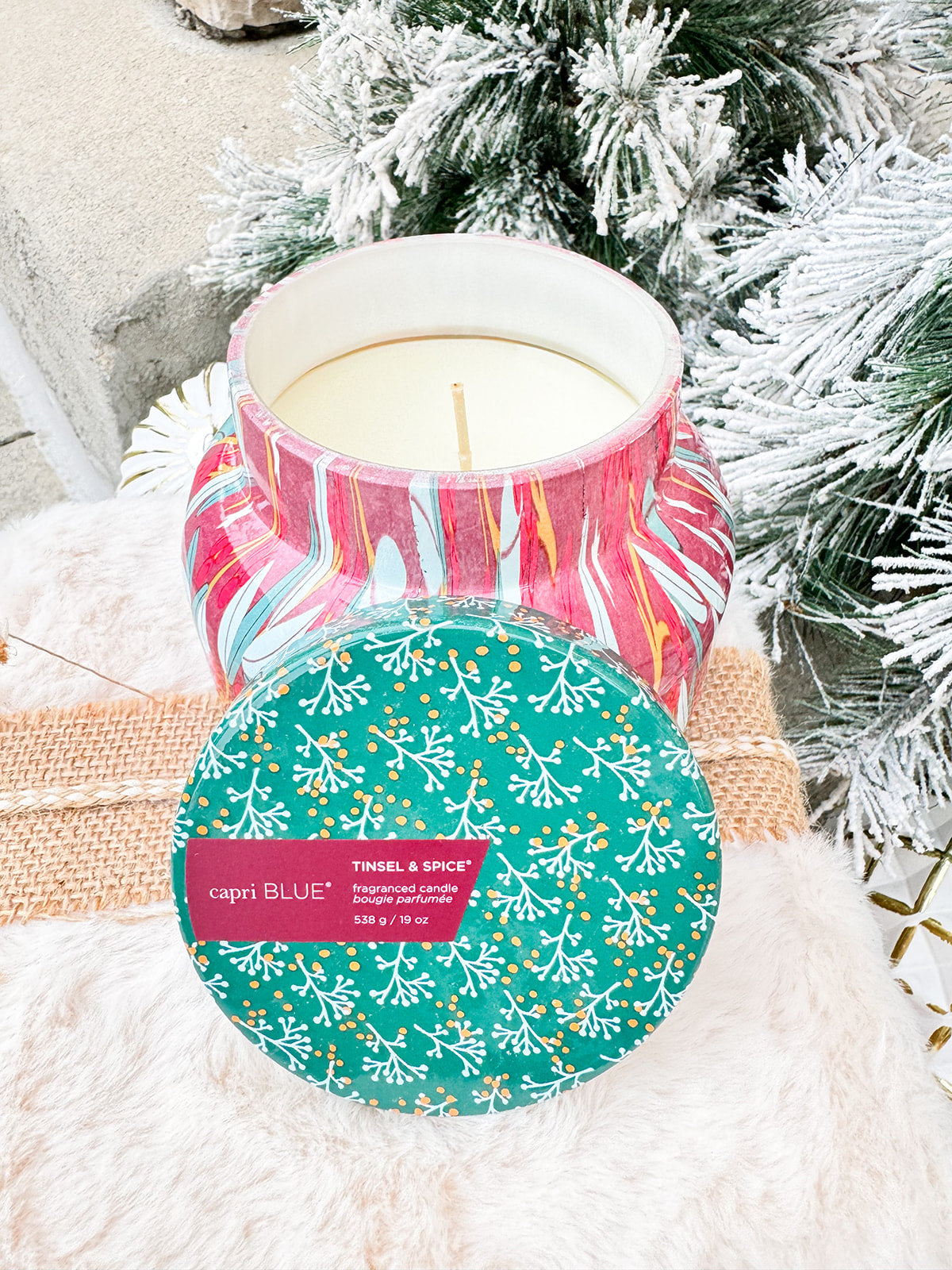 Capri Blue Holiday Pattern Play Tinsel & Spice 19oz candle in red jar with green lid and green, gold, and cream leaf design.