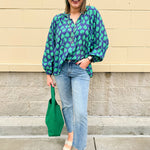 Flowy navy and green patterned blouse with tie-neck, ruffle collar, dolman sleeves, and elastic cuffs—lightweight and oversized