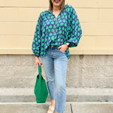 Flowy navy and green patterned blouse with tie-neck, ruffle collar, dolman sleeves, and elastic cuffs—lightweight and oversized