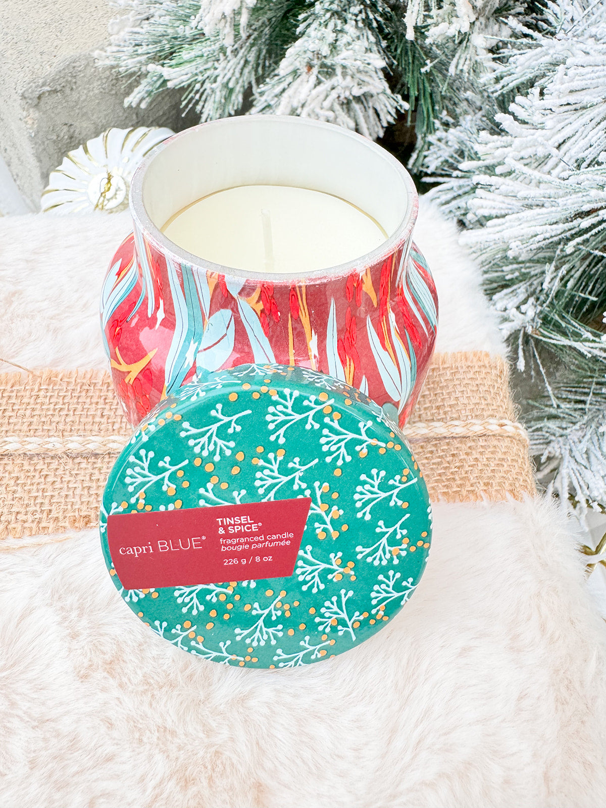 Capri Blue Holiday Pattern Play Tinsel & Spice 8oz candle in red jar with green lid and green, gold, and cream leaf design.