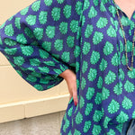 Flowy navy and green patterned blouse with tie-neck, ruffle collar, dolman sleeves, and elastic cuffs—lightweight and oversized