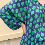 Flowy navy and green patterned blouse with tie-neck, ruffle collar, dolman sleeves, and elastic cuffs—lightweight and oversized
