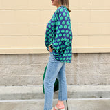Flowy navy and green patterned blouse with tie-neck, ruffle collar, dolman sleeves, and elastic cuffs—lightweight and oversized