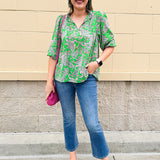 Green and pink paisley print blouse with frilled tie neckline and three-quarter peasant sleeves displayed on hanger against a neutral background