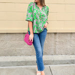 Green and pink paisley print blouse with frilled tie neckline and three-quarter peasant sleeves displayed on hanger against a neutral background
