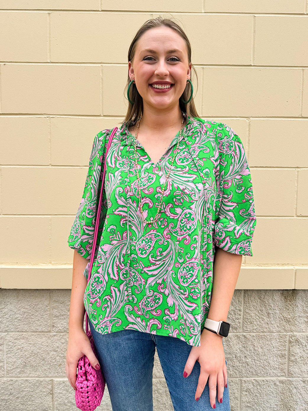 Green and pink paisley print blouse with frilled tie neckline and three-quarter peasant sleeves displayed on hanger against a neutral background