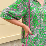 Green and pink paisley print blouse with frilled tie neckline and three-quarter peasant sleeves displayed on hanger against a neutral background