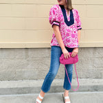 Pink caftan-style top with split neckline and botanical floral print, lightweight and relaxed fit