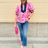 Pink caftan-style top with split neckline and botanical floral print, lightweight and relaxed fit