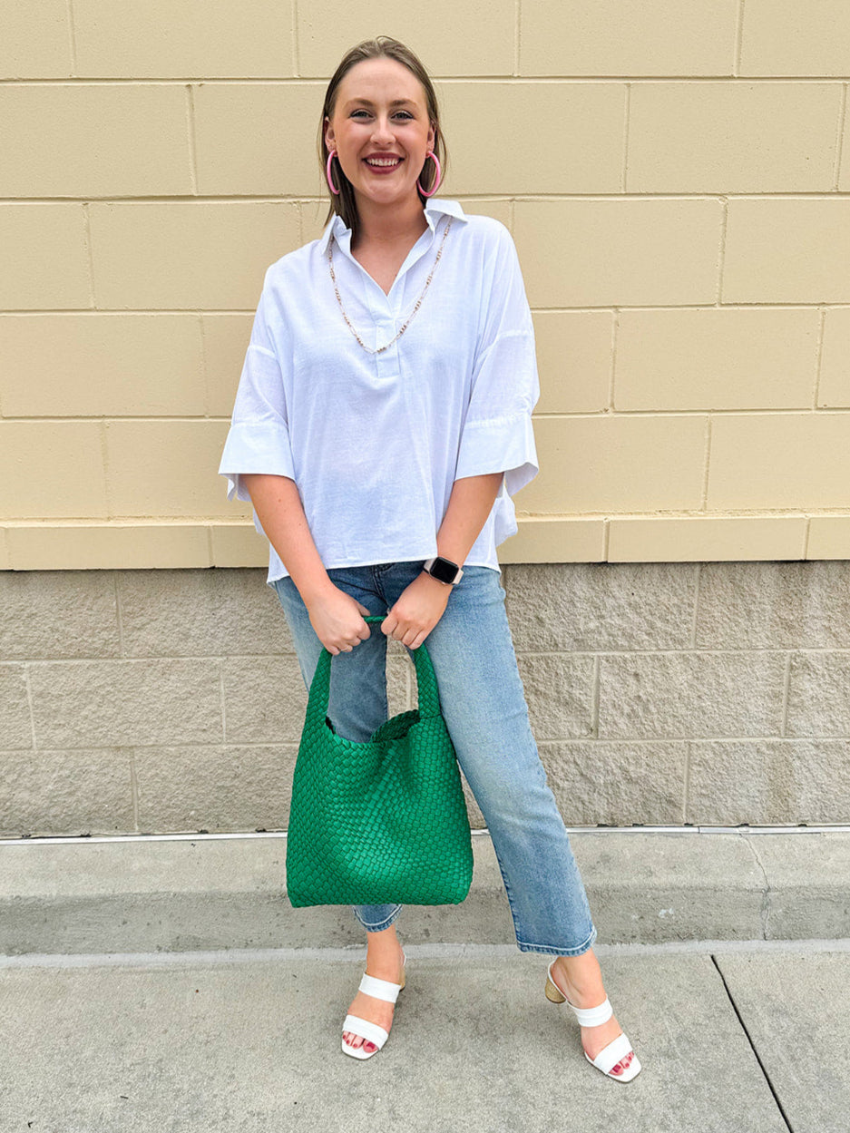 Oversized off-white V-neck popover shirt with collar and cuffed sleeves, styled casually for warm weather.