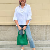 Oversized off-white V-neck popover shirt with collar and cuffed sleeves, styled casually for warm weather.