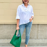 Oversized off-white V-neck popover shirt with collar and cuffed sleeves, styled casually for warm weather.