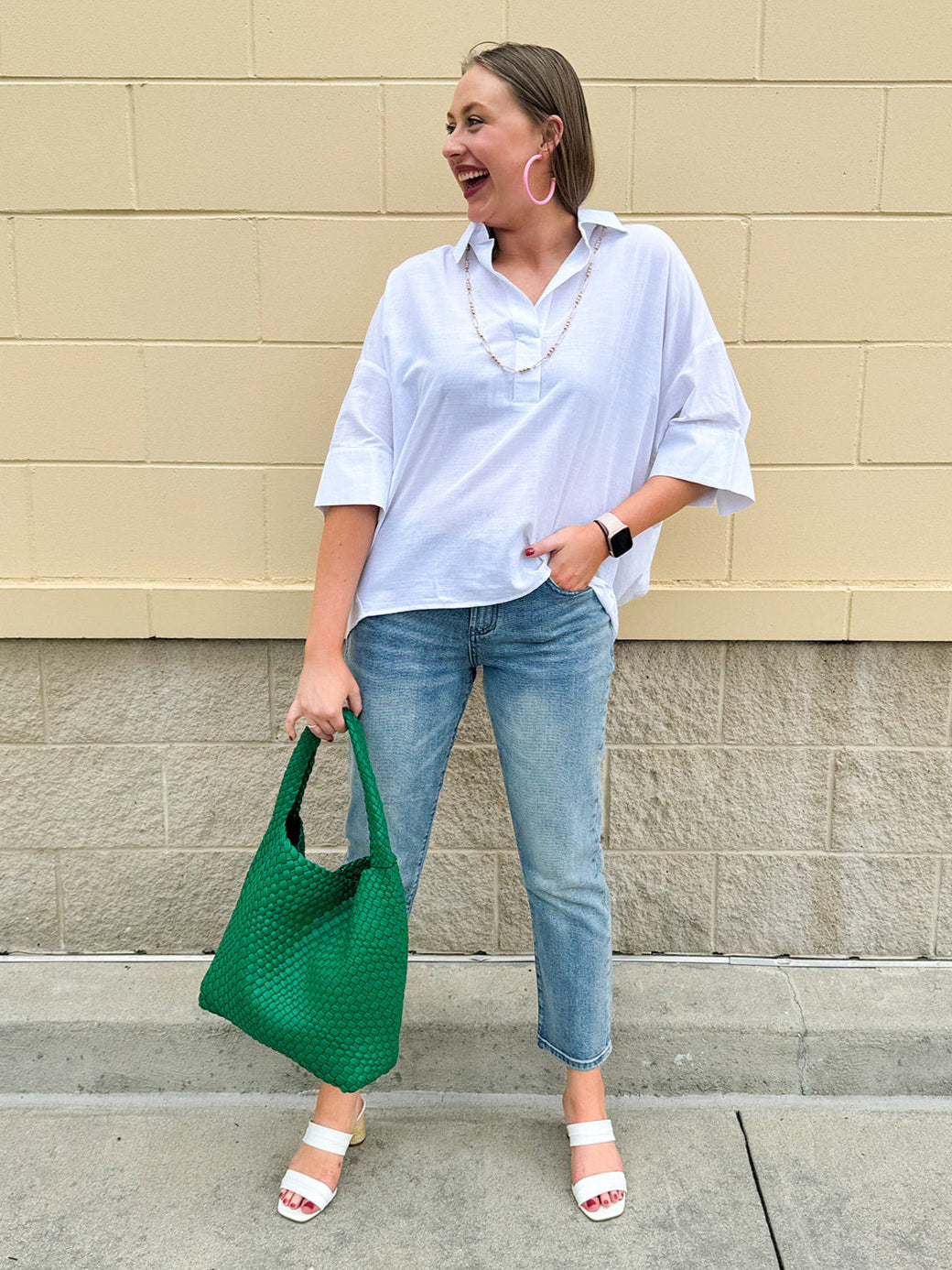 Oversized off-white V-neck popover shirt with collar and cuffed sleeves, styled casually for warm weather.