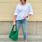 Oversized off-white V-neck popover shirt with collar and cuffed sleeves, styled casually for warm weather.