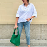 Oversized off-white V-neck popover shirt with collar and cuffed sleeves, styled casually for warm weather.