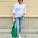 Oversized off-white V-neck popover shirt with collar and cuffed sleeves, styled casually for warm weather.