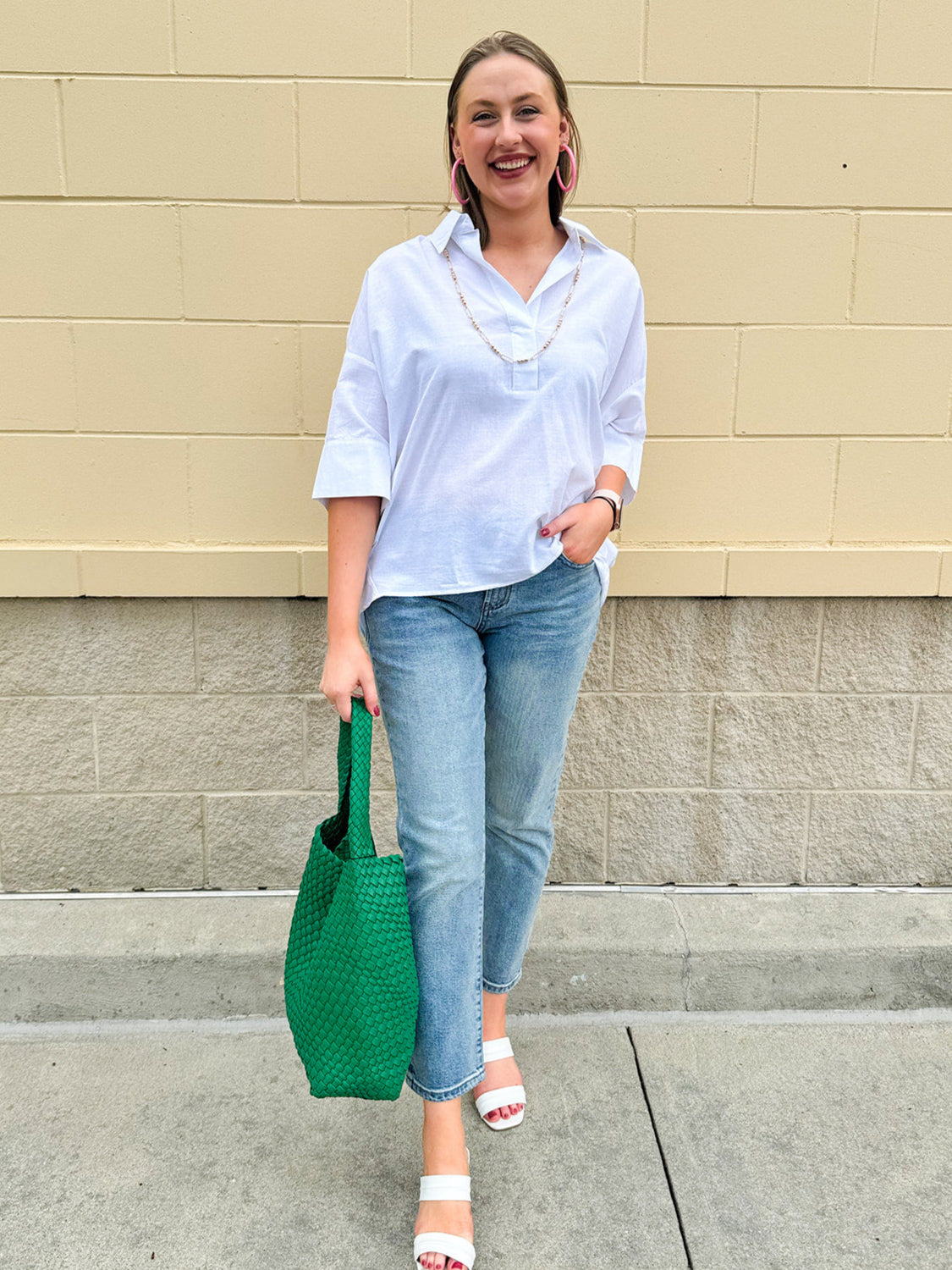Oversized off-white V-neck popover shirt with collar and cuffed sleeves, styled casually for warm weather.