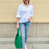 Oversized off-white V-neck popover shirt with collar and cuffed sleeves, styled casually for warm weather.