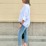 Oversized off-white V-neck popover shirt with collar and cuffed sleeves, styled casually for warm weather.