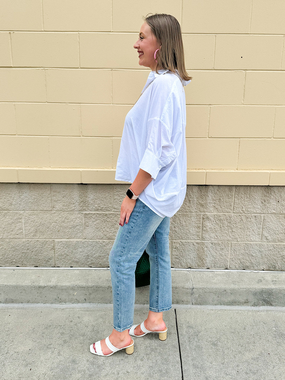 Oversized off-white V-neck popover shirt with collar and cuffed sleeves, styled casually for warm weather.