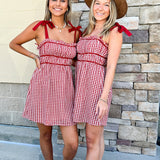 Red and white gingham mini dress with adjustable straps and solid trim detail